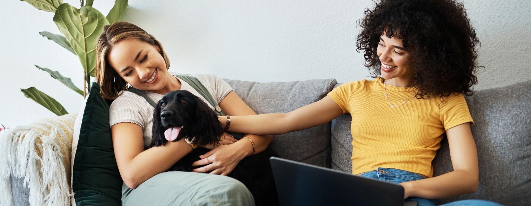 a couple of women sitting on a couch with a dog