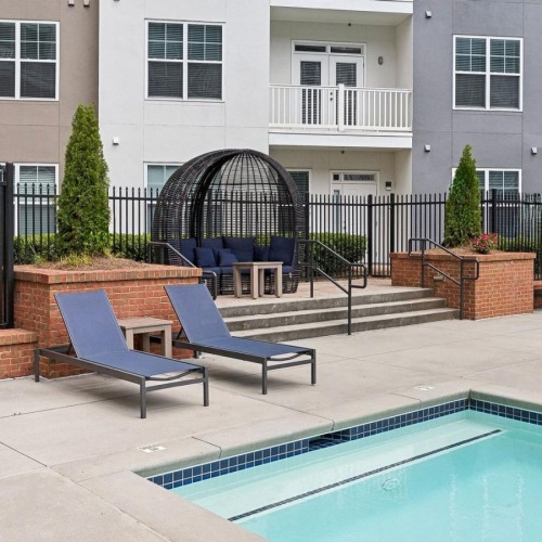a pool and chairs by a building